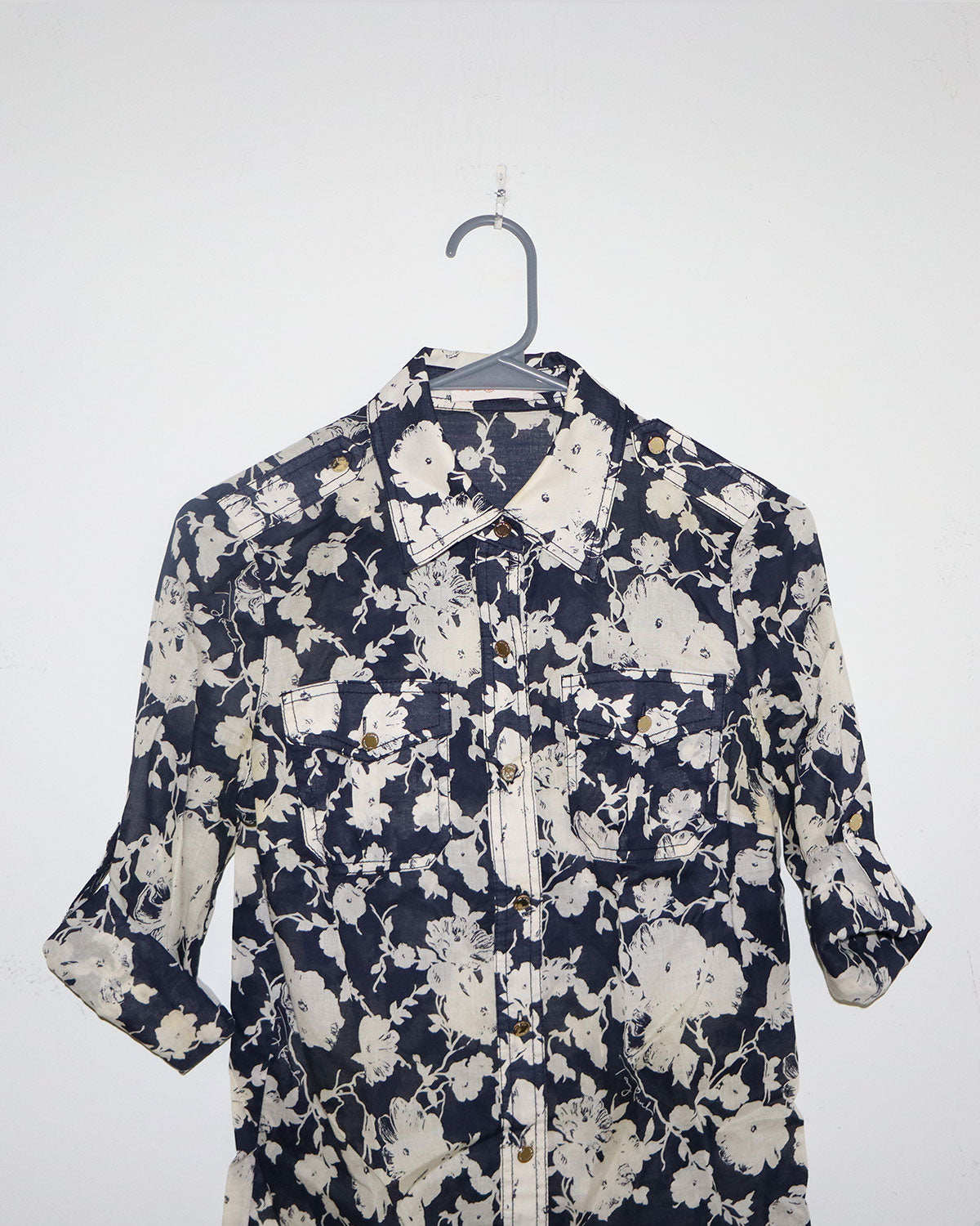 Floral patterned shirt on a hanger against a white background